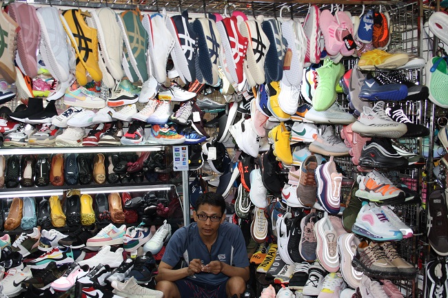 A vendor sells counterfeit shoes based on designs from Nike and Adidas. Counterfeit footwear is among the most popular items amongst Gen Z Shoppers / Alice Sinclair