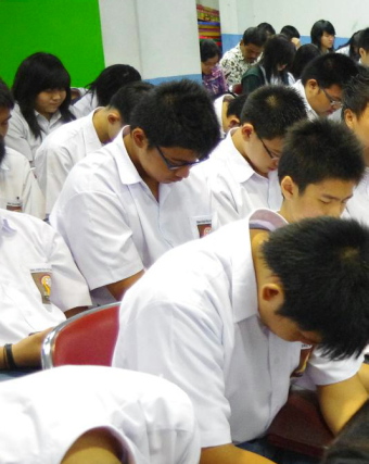 Students praying at a weekly chapel service / Chang-Yau Hoon